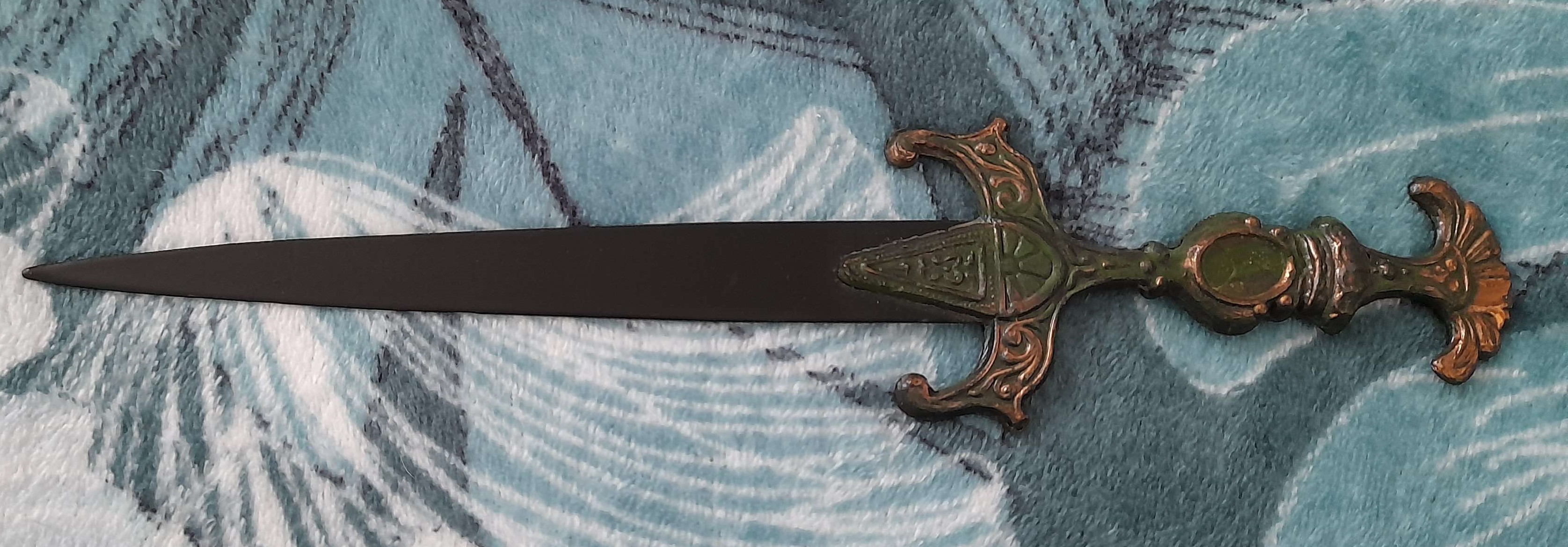 a very cool and ornate looking envelope opener. the blunt blade is black and the handle is dark green with bits of gold