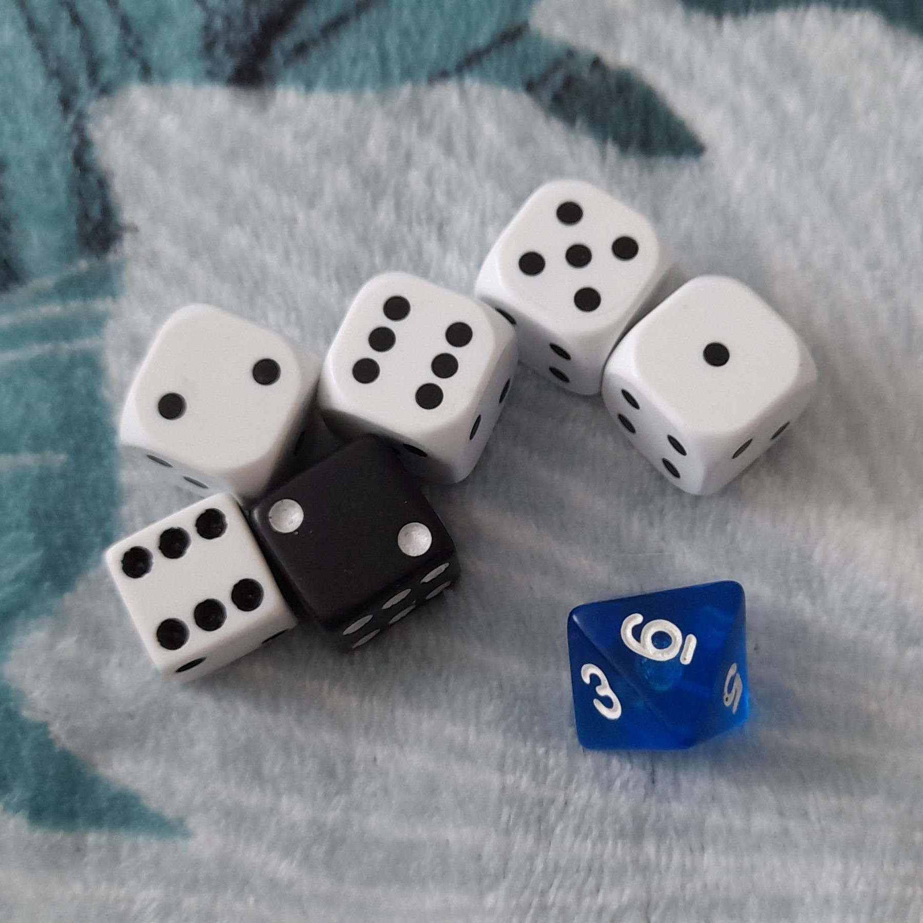 image of seven dice. six of them are six-sided, five white and one black. the seventh dice is blue and eight sided