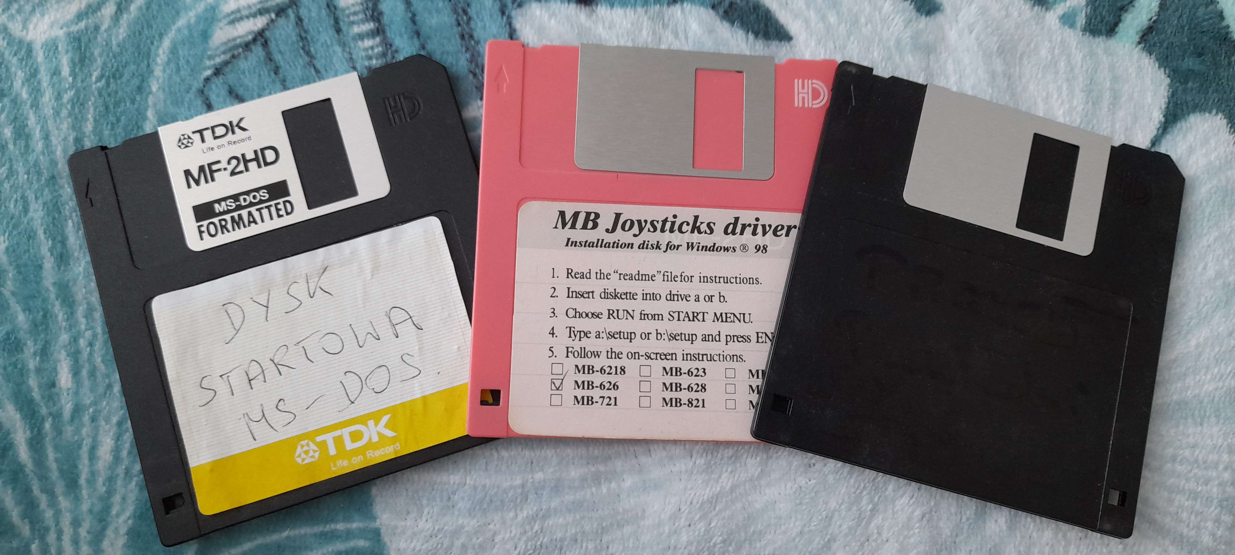 image of three floppy disks. two black, one pink. one of them does't have a label but you can see faint words written in marker