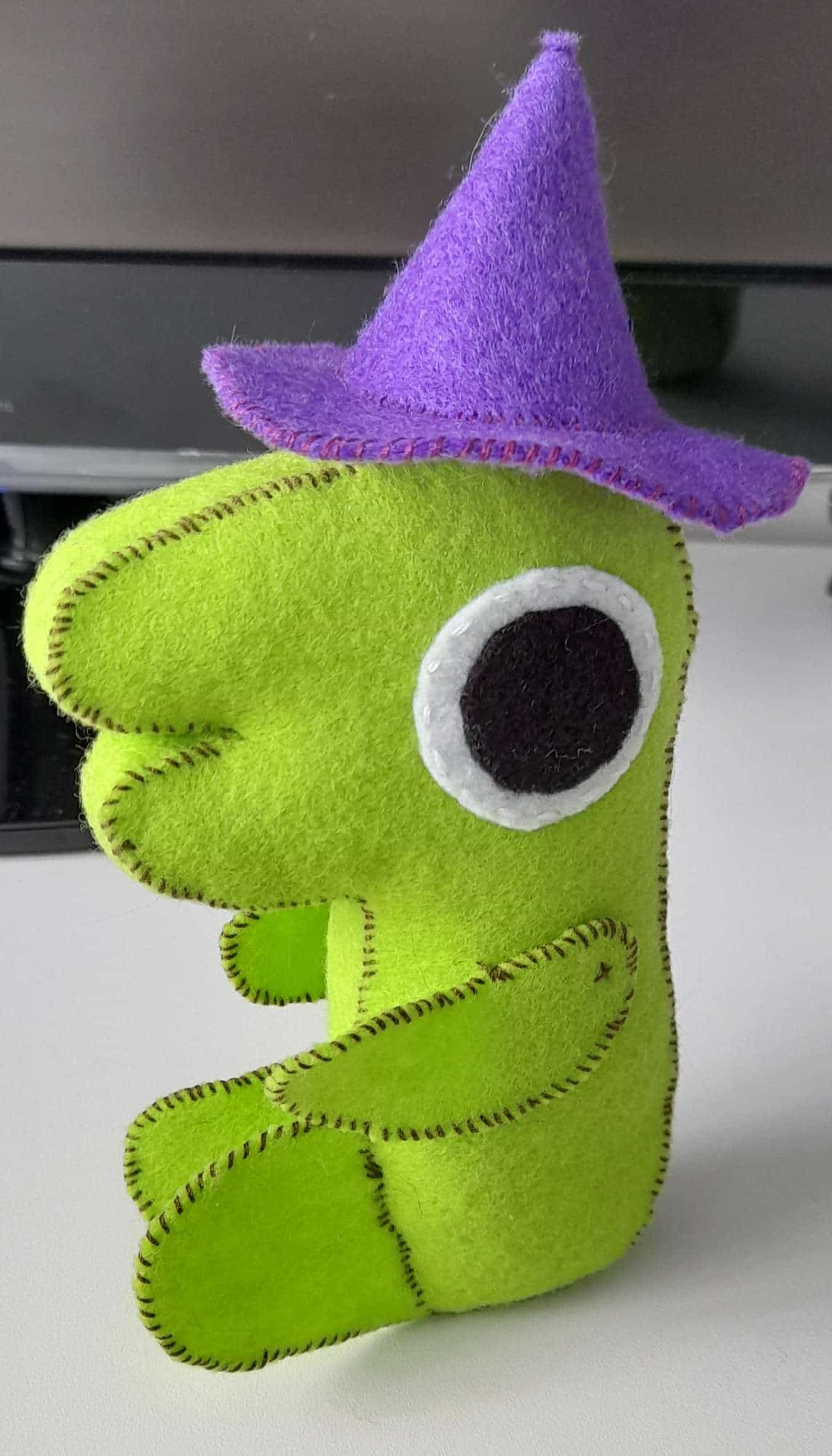 a plushie of glep, a green critter with a purple wizard hat