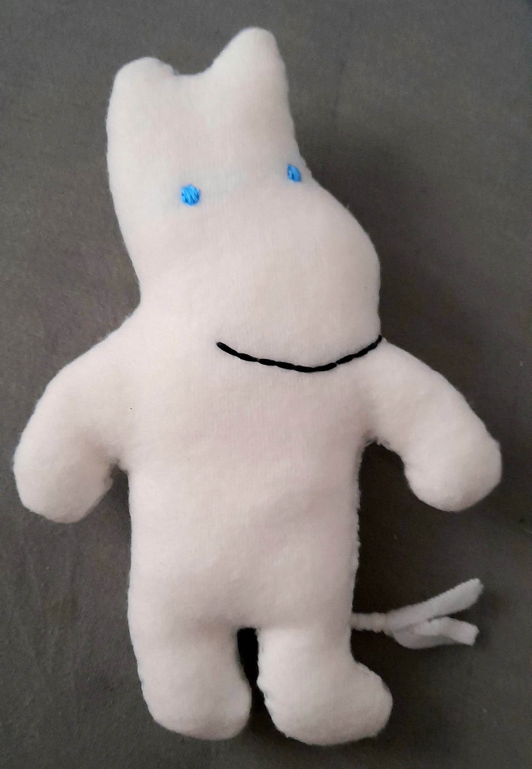 a plushie of moomin troll, a white hippo-like animal with a long thin tail and blue eyes